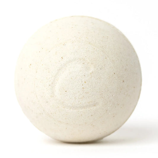 Round, cream-colored oatmeal bath bomb with a textured, speckled surface and a subtle embossed letter C on a white background.