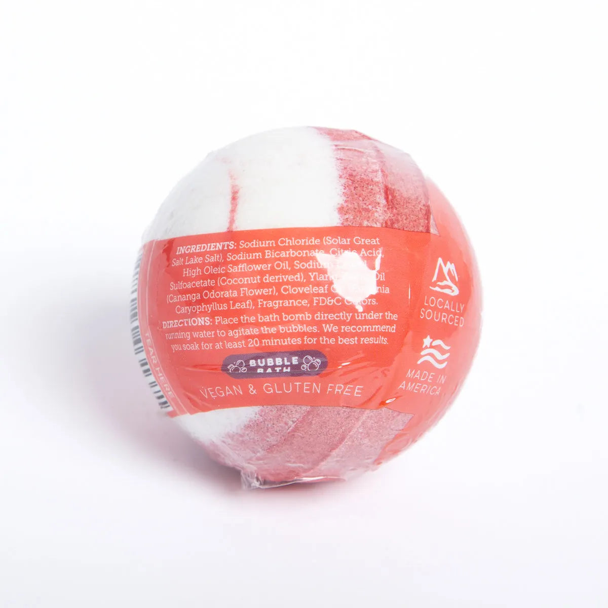 Round Hibiscus Passion bath bomb with red and white swirls, wrapped in clear plastic with printed ingredient information.
